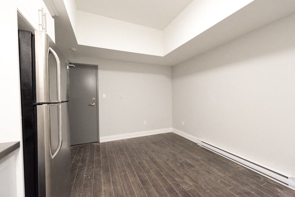 A kitchen with a stainless steel refrigerator and wooden flooring.