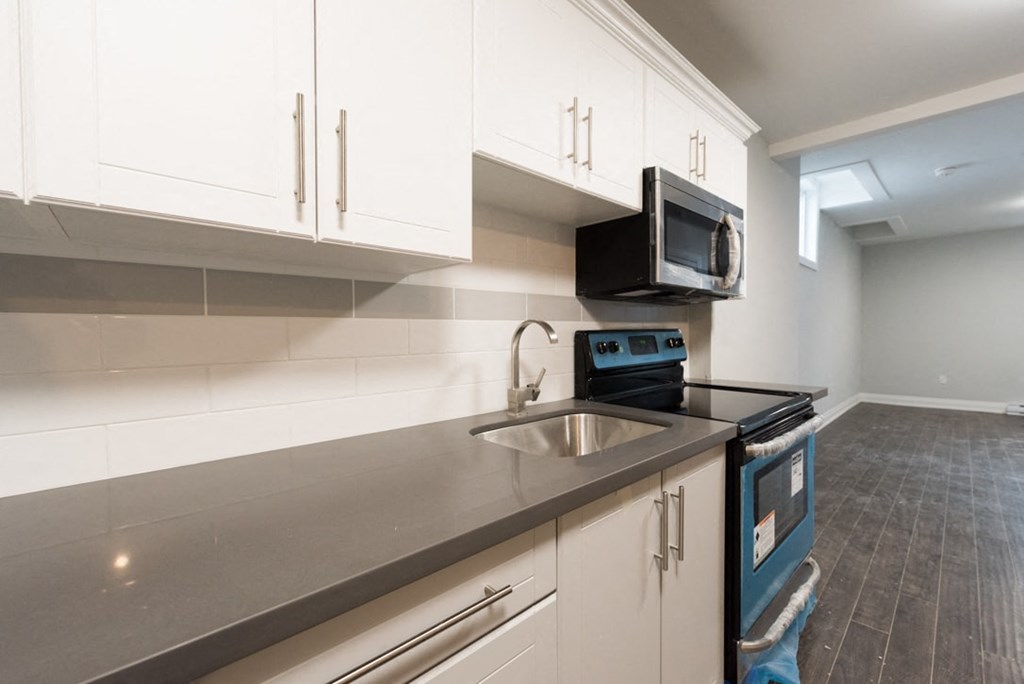 A kitchen with white cabinets and a black microwave above the stove.