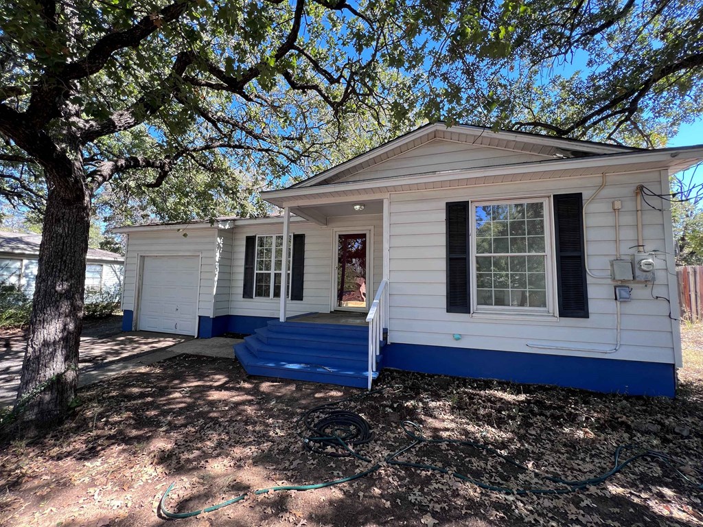 A small white house with a blue trim and a tree in front.