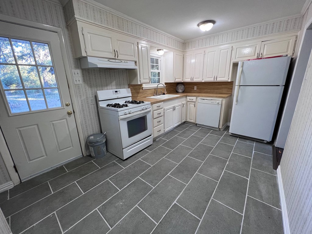 A kitchen with a white stove and a white refrigerator.