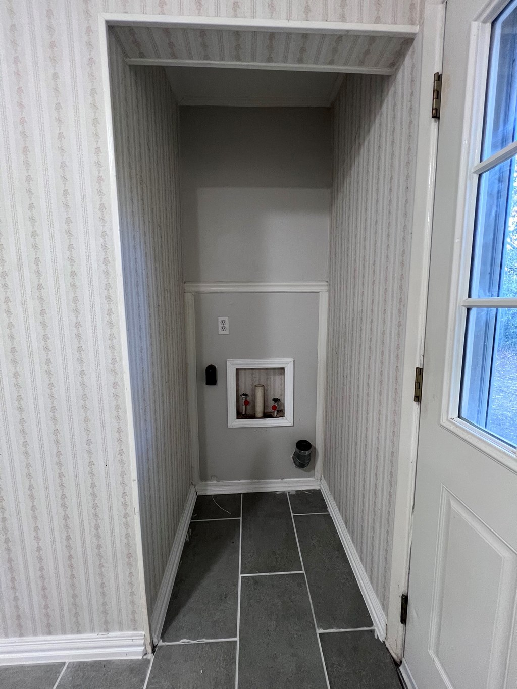 A hallway with a door on the right and a window on the left.
