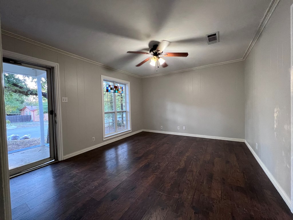 A room with a ceiling fan and sliding glass doors.