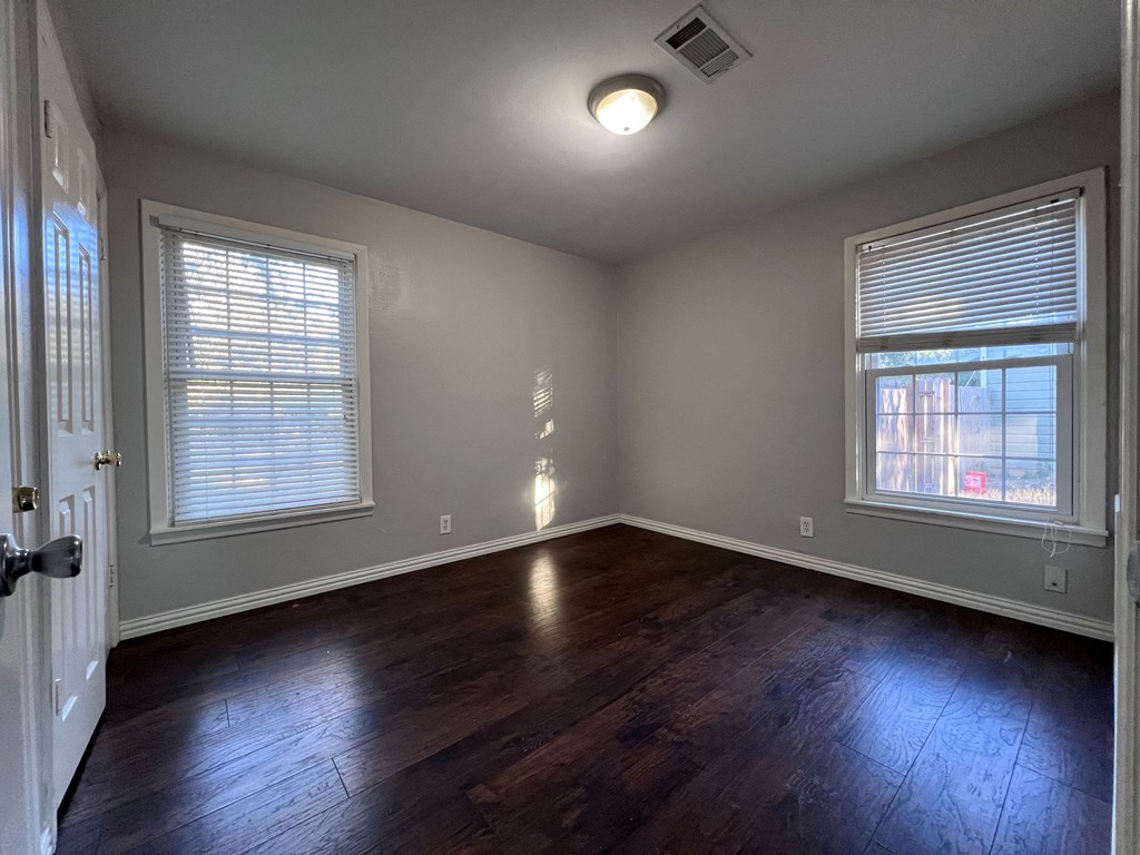 A room with wooden floors and two windows.