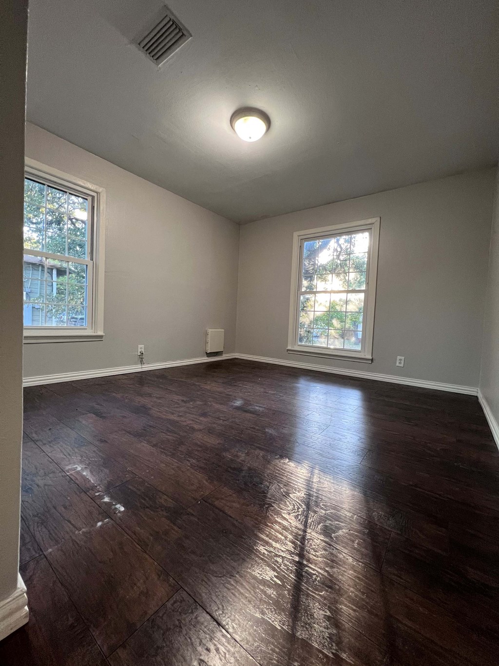 A room with wooden floors and two windows.