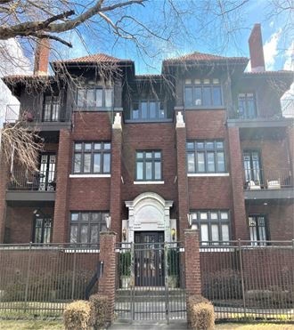 a large brick building with a wrought iron fence in front