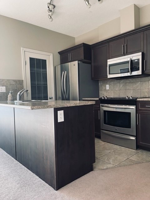 A kitchen with dark brown cabinets and stainless steel appliances.