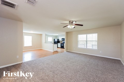A spacious room with a carpeted floor and a ceiling fan.
