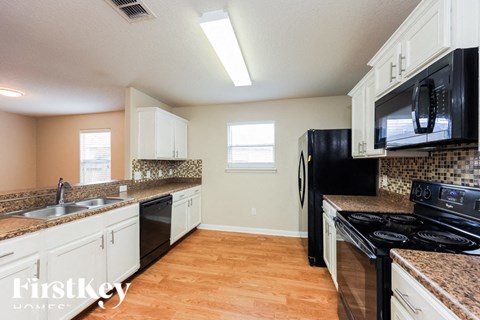A kitchen with a black refrigerator and white cabinets.
