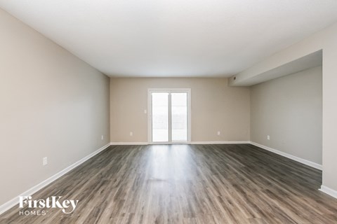 A spacious room with wooden flooring and a large window.