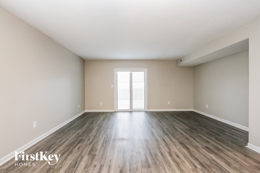 A spacious room with wooden flooring and a large window.