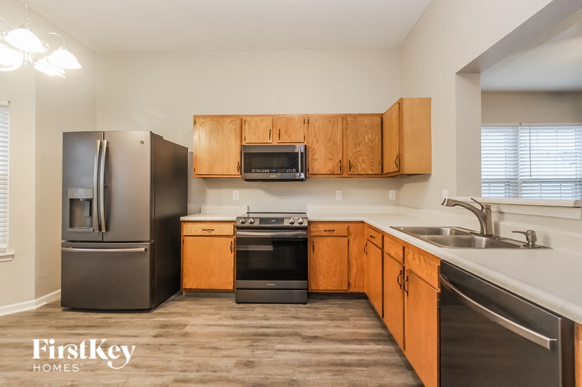 A kitchen with wooden cabinets and a black fridge.