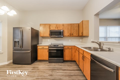 A kitchen with wooden cabinets and a black fridge.