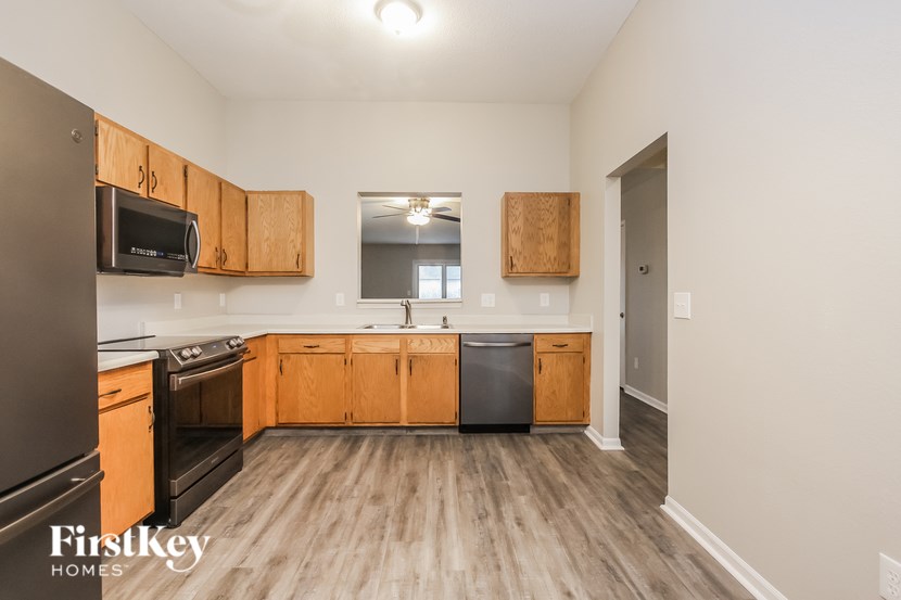 A kitchen with wooden cabinets and a black refrigerator.