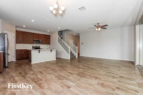 A spacious living room with wooden flooring and a staircase leading to the upper level.