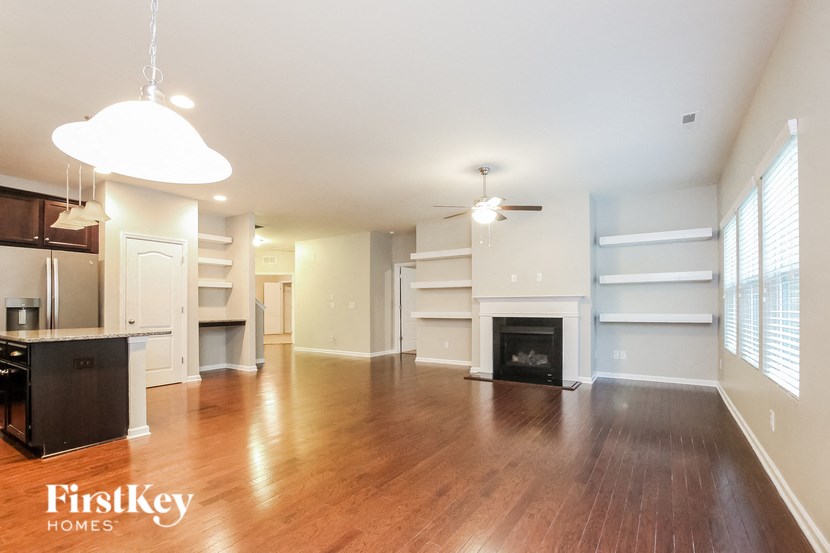 A spacious living room with wood flooring and a fireplace.