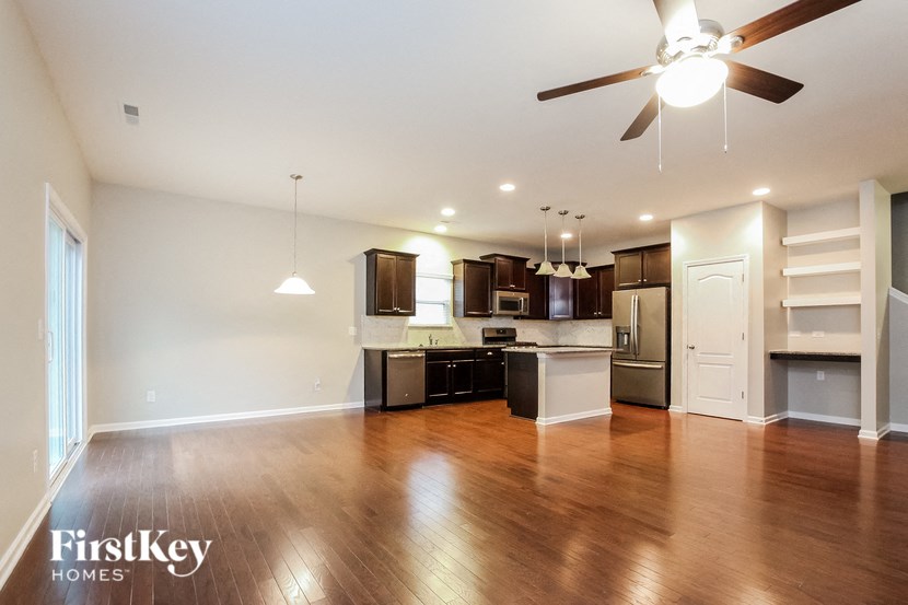 A spacious kitchen with wooden floors and a ceiling fan.