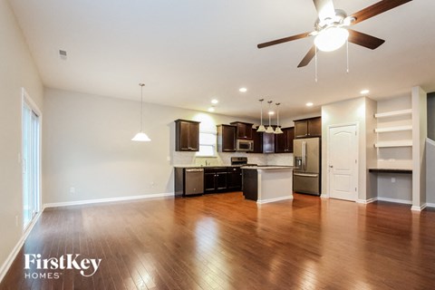 A spacious kitchen with wooden floors and a ceiling fan.