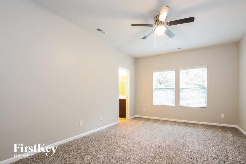 A spacious room with a ceiling fan and carpeted floor.