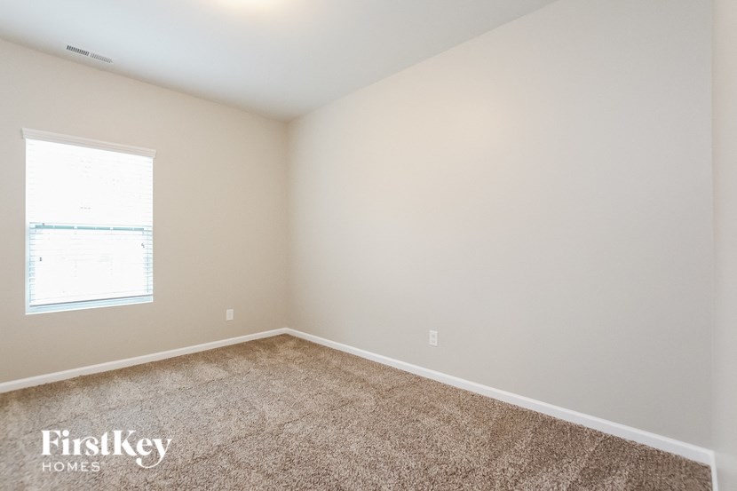 A room with a carpeted floor and a window letting in light.