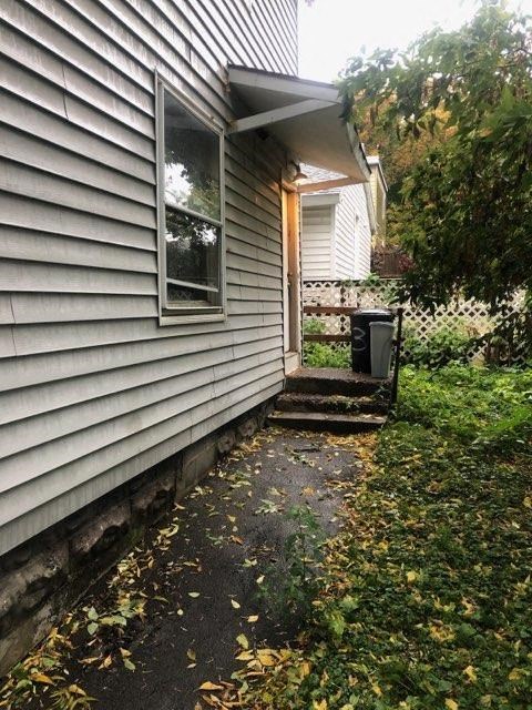 the side of a white house with a porch and a backdoor