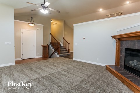A spacious living room with a fireplace and a staircase.