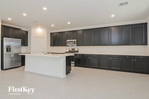 A kitchen with black cabinets and a white island.