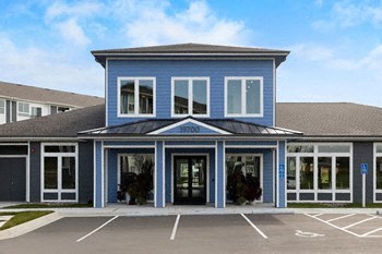 the front of a blue building with a parking lot