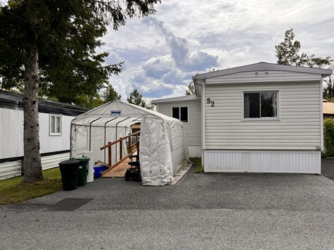 A white house with a number 52 on it and a white tent in front.