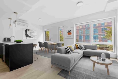 A modern living room with a grey sofa and a black kitchen island.