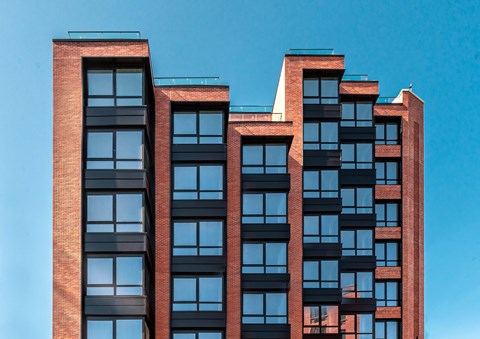 A red brick building with black windows and balconies.