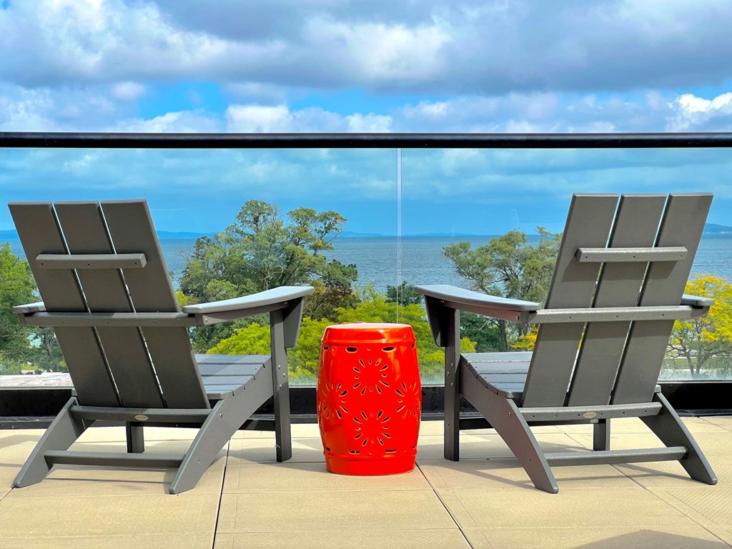 two chairs and a table on a balcony overlooking the ocean