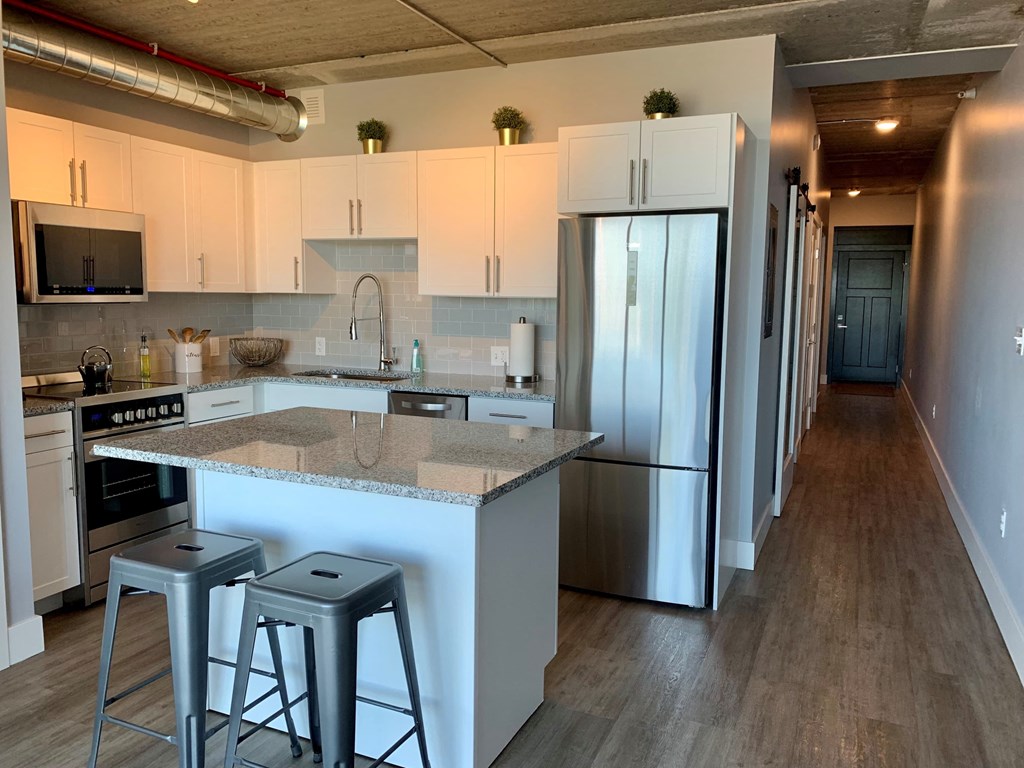 a kitchen with a center island and a stainless steel refrigerator