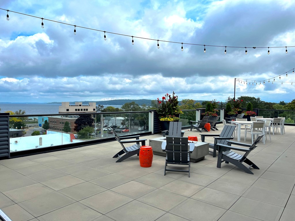 a rooftop terrace with tables and chairs overlooking a pool and the ocean