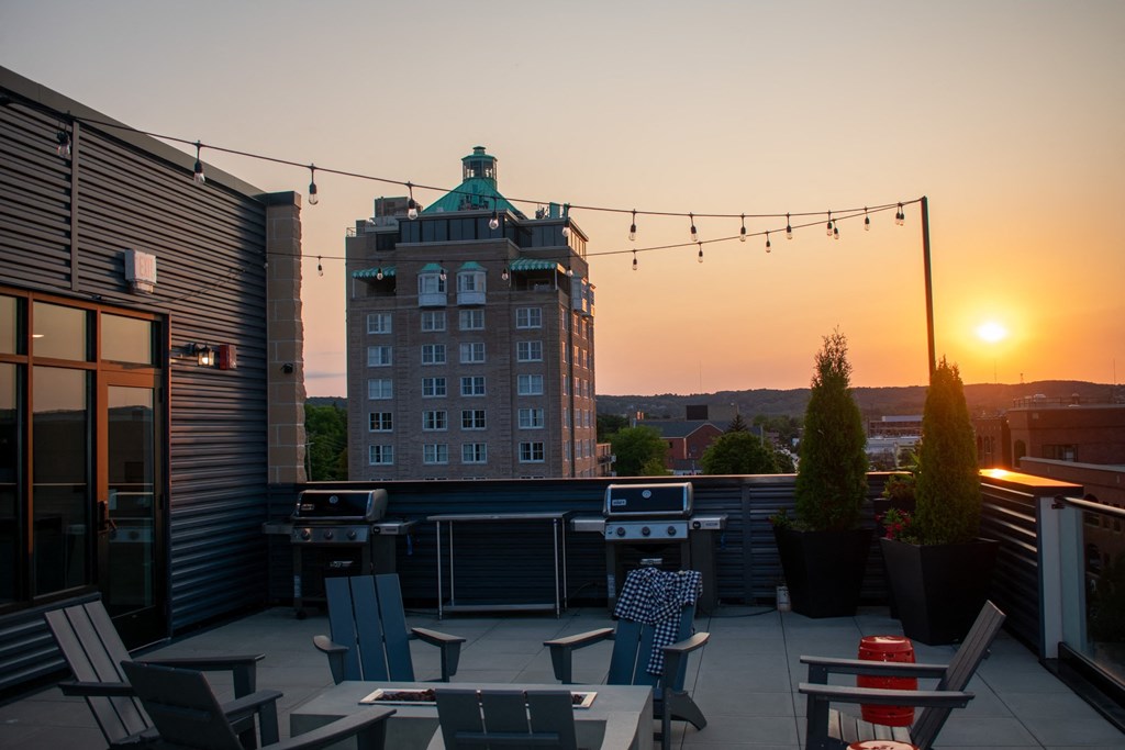 a rooftop bar with a building in the background at sunset