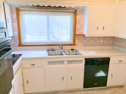 a kitchen with white cabinets and a sink and a window