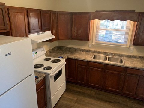 A kitchen with a white fridge, stove and sink.