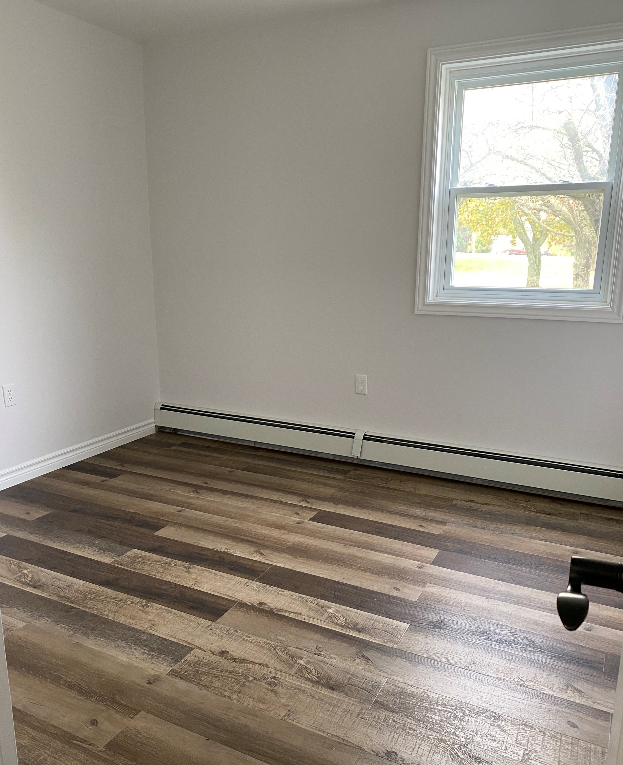 A room with a window and a wooden floor.