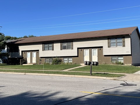 A two-story residential building with a brown roof and beige siding.