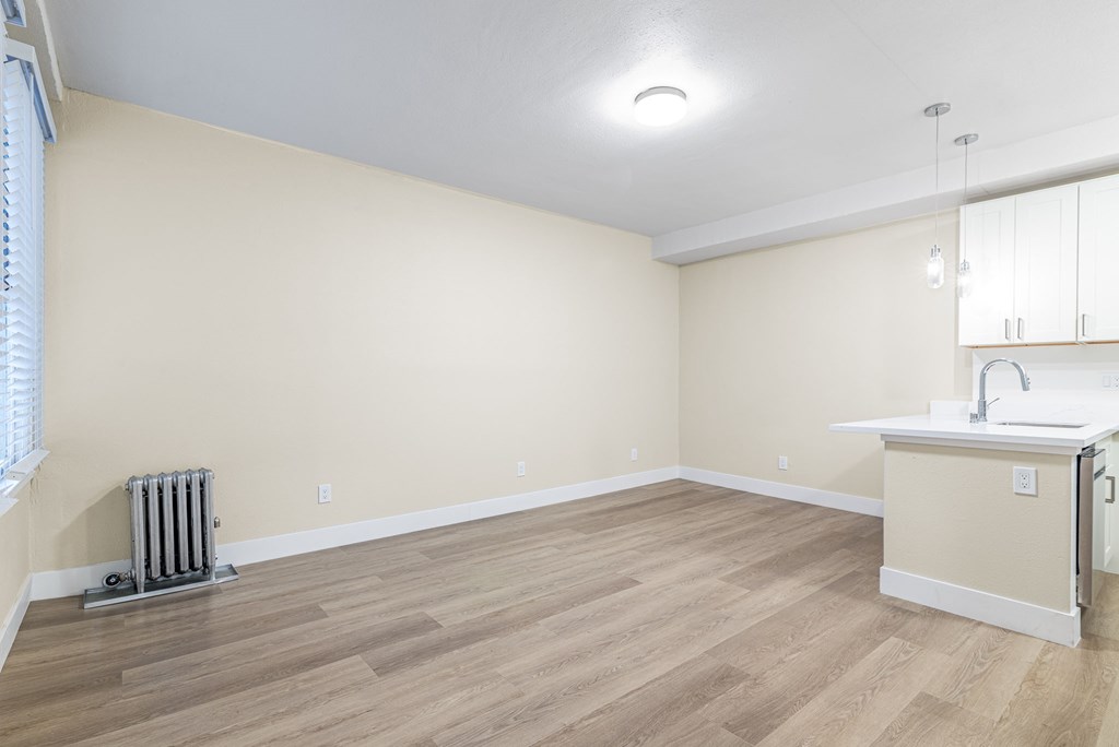 the living room and kitchen of an empty house with wood flooring