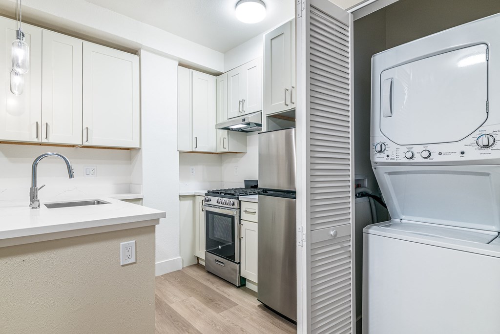 a white kitchen with a washer and dryer and white cabinets