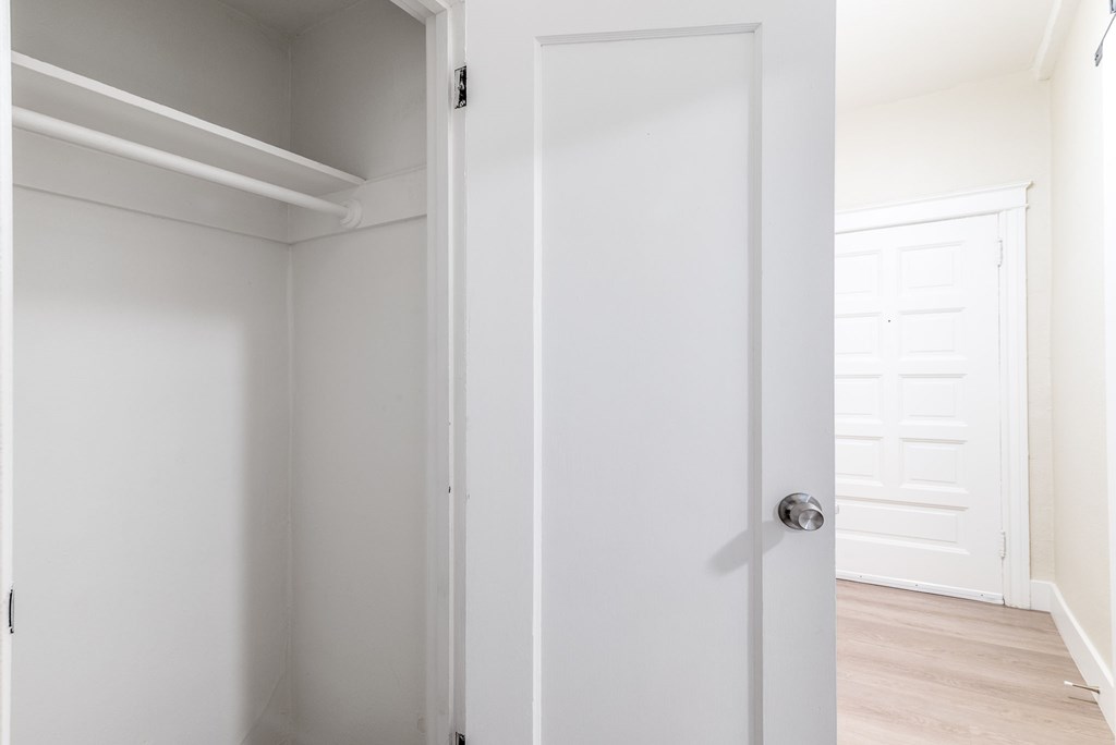 an empty room with a white door and a white closet