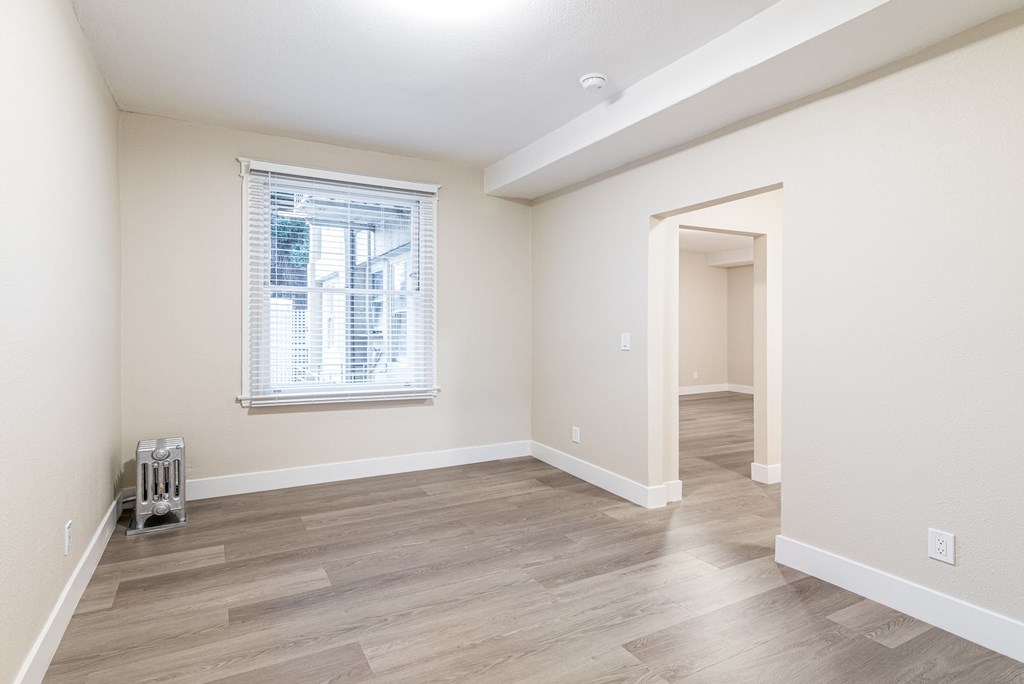 an empty living room and hallway with a window and wood flooring