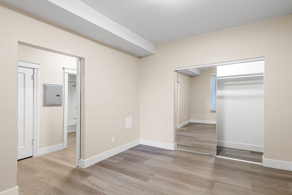 the living room and dining room of an apartment with a mirrored door