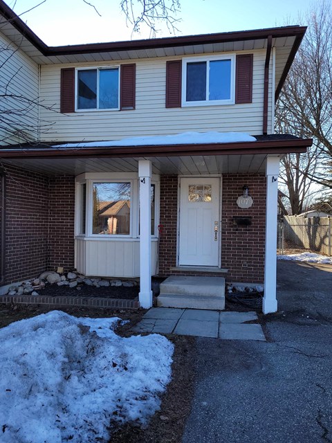 a white door on a brick house with snow on the sidewalk