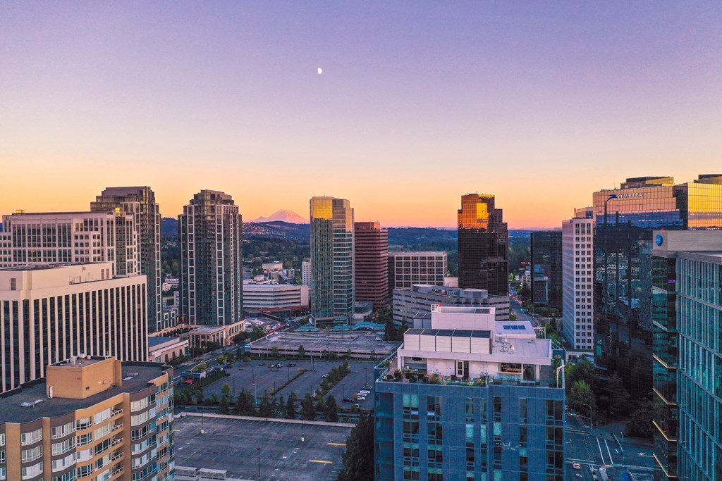 a city skyline at sunset with the moon in the sky