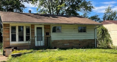 a small yellow and with a porch and grass