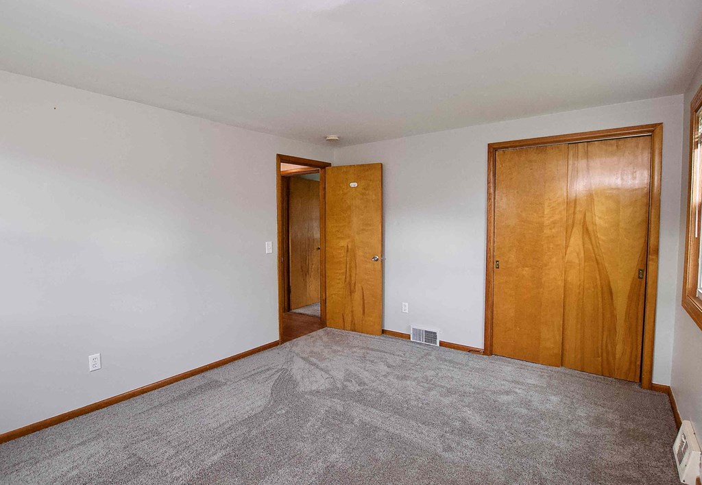 a bedroom with a carpeted floor and a door to a closet