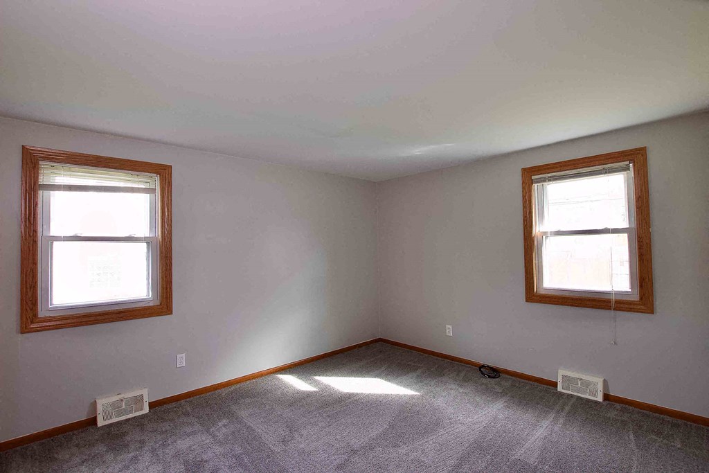 an empty room with two windows in it