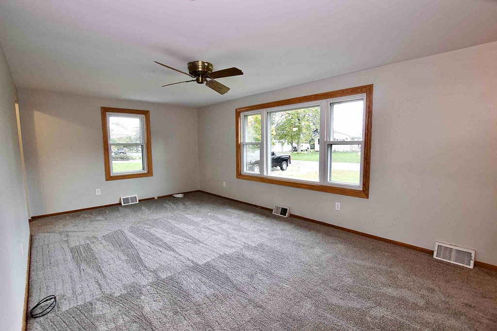 an empty living room with a ceiling fan and a window