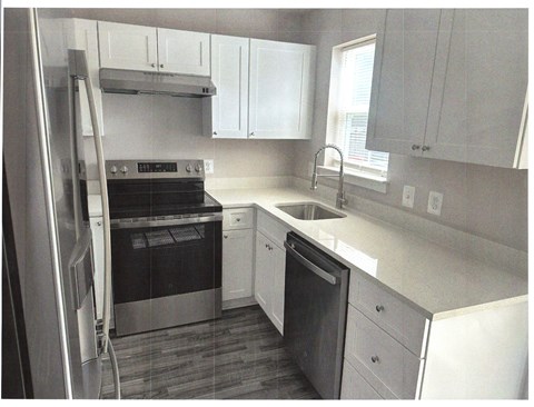 A kitchen with white cabinets and a stainless steel refrigerator.
